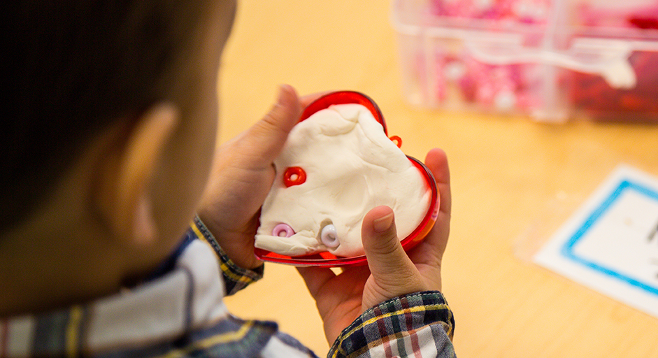 Image of child holding heart and playdough